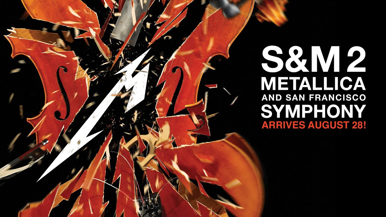 Metallica and the San Francisco Symphony performing on a red-lit concert stage.